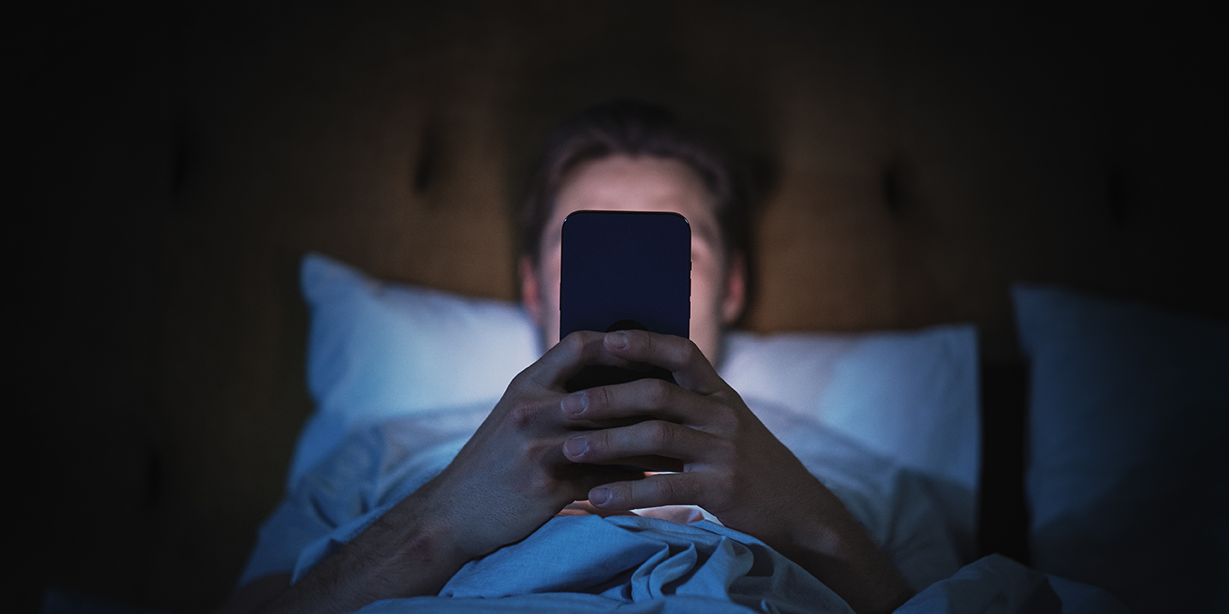 quelqu'un allongé dans le noir, éclairé par l'écran de son téléphone